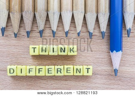 Words Think Different motivational slogan on wooden table with group of pencils. Top view. Think Different business unique and success concept