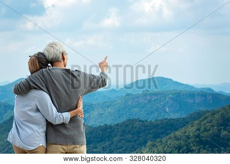 Asian Lifestyle Senior Couple Hug And Pointing The Mountain Nature.  Old People Happy In Love Romant