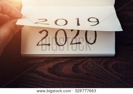 New Year 2020 Coming Concept. Male Fingers Flips Notepad Or Calendar Sheet. 2019 Is Turning, 2020 Is