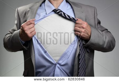 Businessman in classic superman pose tearing his shirt open to reveal t shirt with blank chest for message