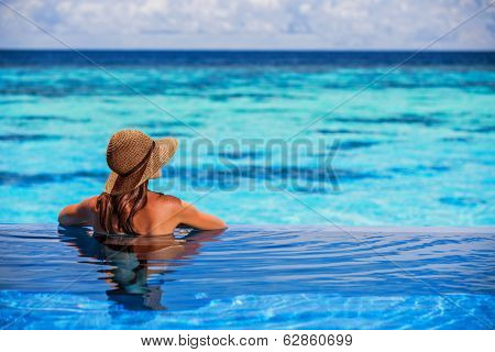 Relaxing on beach resort, back side of sexy woman enjoying seascape from endless pool, luxury summer vacation, travel and tourism concept