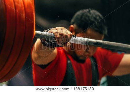 male powerlifter preparing for squats with a barbell during competition of powerlifting