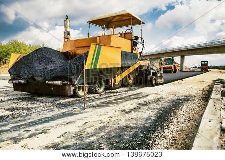 New Road - Pavement machine laying fresh asphalt or bitumen on top of the gravel base during highway construction