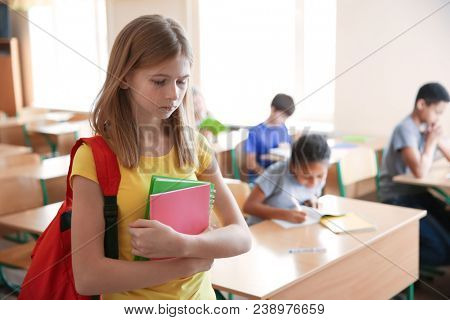 Sad teenage girl in classroom. Bullying at school