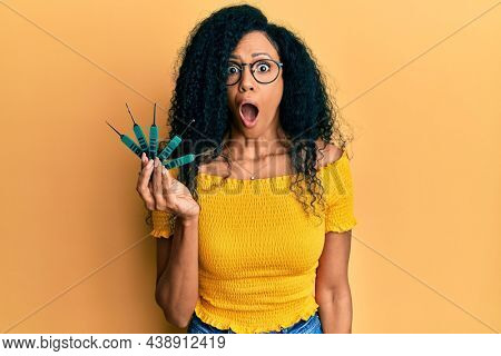 Middle age african american woman holding picklock to unlock security door scared and amazed with open mouth for surprise, disbelief face 