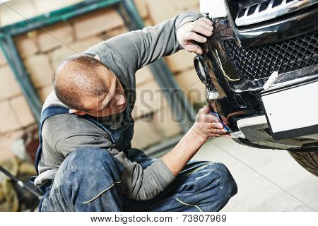 auto mechanic worker sanding polishing bumper car at automobile repair and renew service station shop by sandpaper