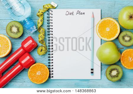 Diet plan menu or program, tape measure, water dumbbells and diet food of fresh fruits on white background. Weight loss and detox concept. Top view, flat lay.