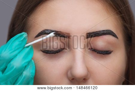 Master corrects makeup and gives shape and color to the eyebrows with henna in a beauty salon 