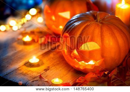 Halloween pumpkin head jack lantern with burning candles over wooden background. Halloween holidays art design, celebration. Carved Halloween Pumpkins with burning candles