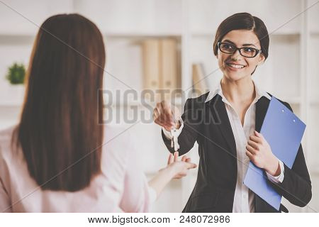 Smiling Realtor Holding Tablet And Giving Keys To Woman. Real Estate Sales Concept. Getting Access T