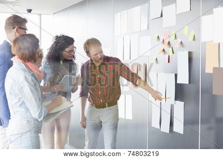 Young businessman explaining document to colleagues in creative office