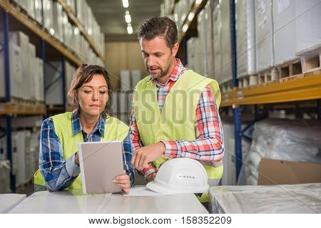 Man and a woman have short meeting in a warehouse in checking inventory levels of goods. First in first out Last in last out team working together concept photo.