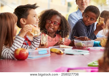 Young school kids eating lunch talking at a table together