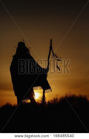 Silhouette Of Native American Shaman With Pikestaff On Background Of Sunset Beutiful In Mountains