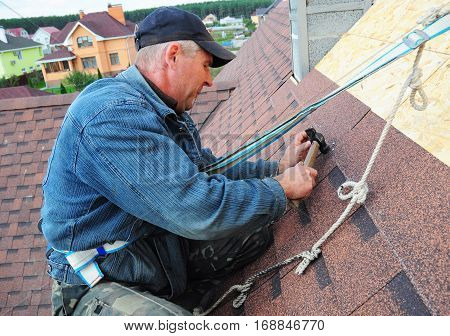 KYIV UKRAINE - February  14 2017:  Roofing Contractor. Roofing Construction and Building New House Exterior. Roofer Install Repair Asphalt Shingles or Bitumen Tiles on the Rooftop Outdoor.