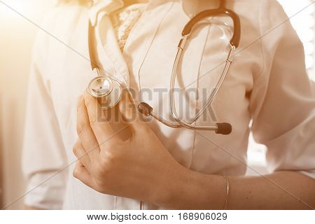 Female Medicine Therapeutist Doctor Hands Holding Stethoscope On His Chest In Office Closeup. Medica