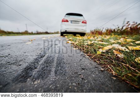 Close Up Of Car Brake Path On Edge Of Asphalt Road On The Background Of Parked White Car, Fallen Yel