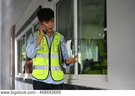 Engineer Man In Yellow Vests Having Phone Conversation While Working In Building Construction Site