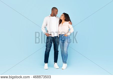 Full Length Shot Portrait Of Black Couple Hugging And Looking At Each Other, Posing On Blue Backgrou