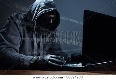 Computer hacker stealing data from a laptop concept for network security, identity theft and computer crime