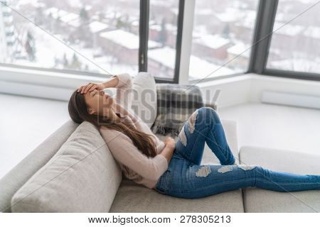 Headache and depression - winter blues anxiety woman feeling sick holding head and stomach in pain - menstrual period pain or tired.