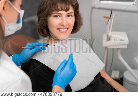 Smiling Girl In Dentist's Chair Looks At Her Doctor With Confidence, And Then Turns Her Gaze Directl