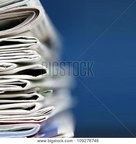 Stack of newspaper on blue background close up