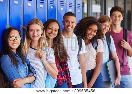 Teenage school kids smiling to camera in school corridor