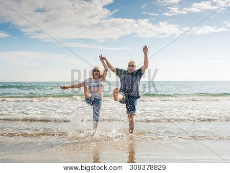 Senior Couple In Love Walking On The Beach Having Fun In A Sunny Day