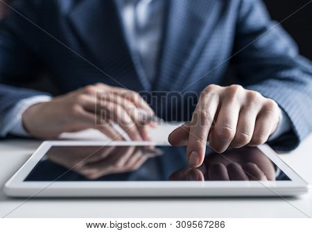 Close-up Of Male Hand Touching Screen Of Digital Tablet. Man In Business Suit Sitting At Desk And Wo