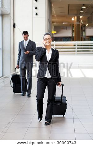 businesspeople walking in airport with luggage