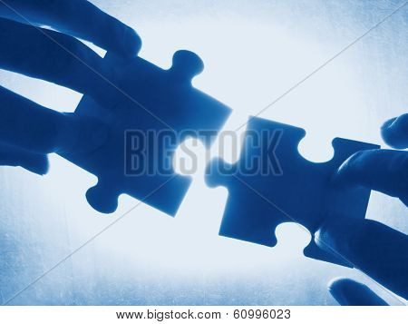 hands trying to fit two puzzle pieces together