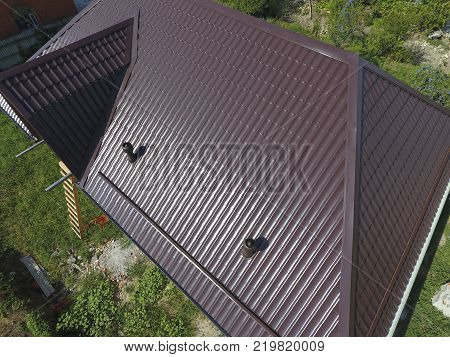 The roof of corrugated sheet. Roofing of metal profile wavy shape. A view from above on the roof of the house.