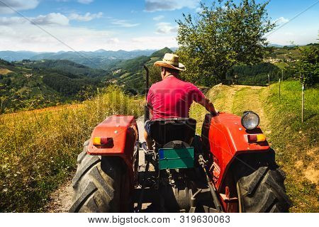 Man Driving Tractor In Agricultural Fields. Agricultural Worker Driving Tractor In Nature. Man Worki