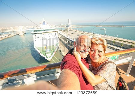 Senior happy couple taking selfie on ship at Barcelona harbour background - Mediterranean cruise travel tour - Active elderly concept with retired people around the world - Warm afternoon color tones