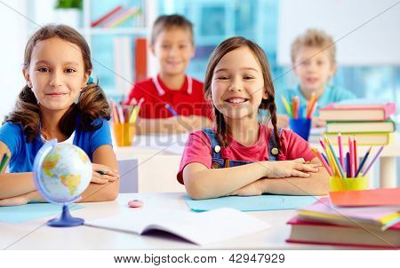 Portrait de deux jeunes filles diligents, regardant la caméra au lieu de travail avec les écoliers sur fond