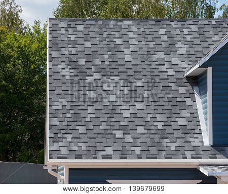 The roof of the house lined with gray bitumen shingles