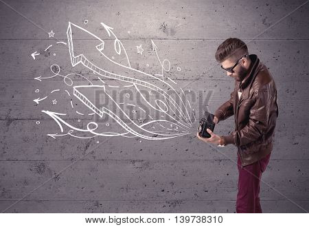 A hipster guy opening his point of view through looking a vintage camera concept with illustratied drawn arrows on urban wall