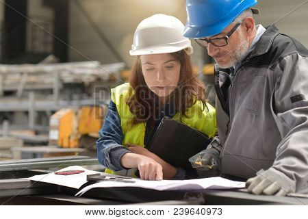 Metalworker and engineer meeting in factory