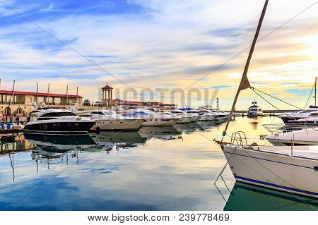 Luxury Yachts And Motor Boats At Sunset. Sailing Boats Docked At Pier In Marina In Sunshine, Blue Wa