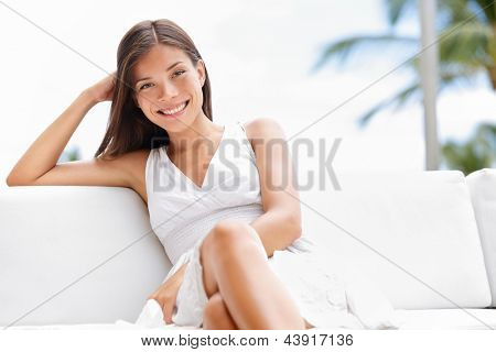 Portrait of young happy confident asian woman sitting outside in sofa smiling at camera with professional self assured confidence. Beautiful multicultural woman in luxury setting outside.