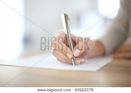 Closeup of woman's hand writing on paper