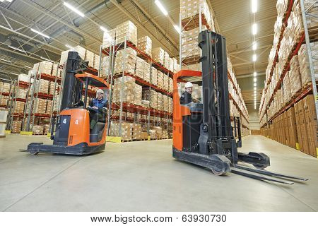 two young workers men in uniform at warehouse with forklift facilities