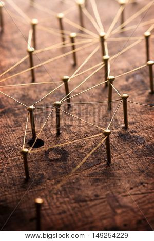 Linking entities. Network, networking, social media, internet communication abstract. A small network connected to a larger network. Web of gold wires on rustic wood. Shallow depth of field.