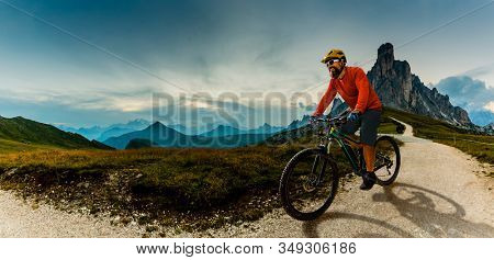 Single mountain bike rider on electric bike, e-mountainbike rides up mountain trail. Man riding on bike in Dolomites mountains landscape. Cycling e-mtb enduro trail track. Outdoor sport activity.