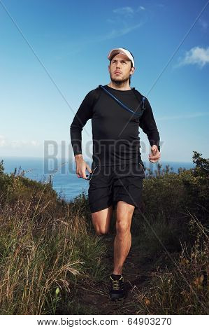 fitness running man on mountain trail near ocean exercising for marathon training