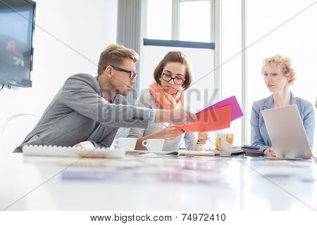 Creative businesspeople analyzing documents at desk in office