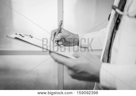 Close-up Of Male Doctor Filling The Medical Form black and white. Close-up Of Male Doctor Filling The Medical Form. Doctor writting. Uniform doctor. Doctor man. Doctor woman. Doctor paperwork. Pen in hand doctor.