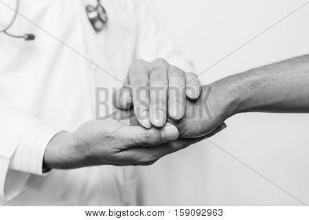 Two people holding hands for comfort black and white.doctor's hands holding patient's hand for encouragement and empathy. Doctor concept. Doctor man. Doctor support. Doctor talk. Doctor trust. Doctor shake. Doctor waiting