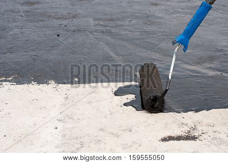 Roofer worker painting black coal tar or bitumen at concrete surface by the roller brush A waterproofing.